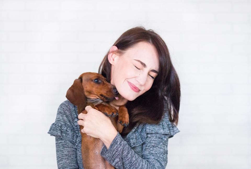Smiling woman holding a dachshund in her arms